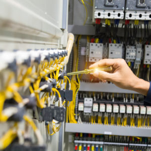 Electricians hands testing current  electric in control panel.